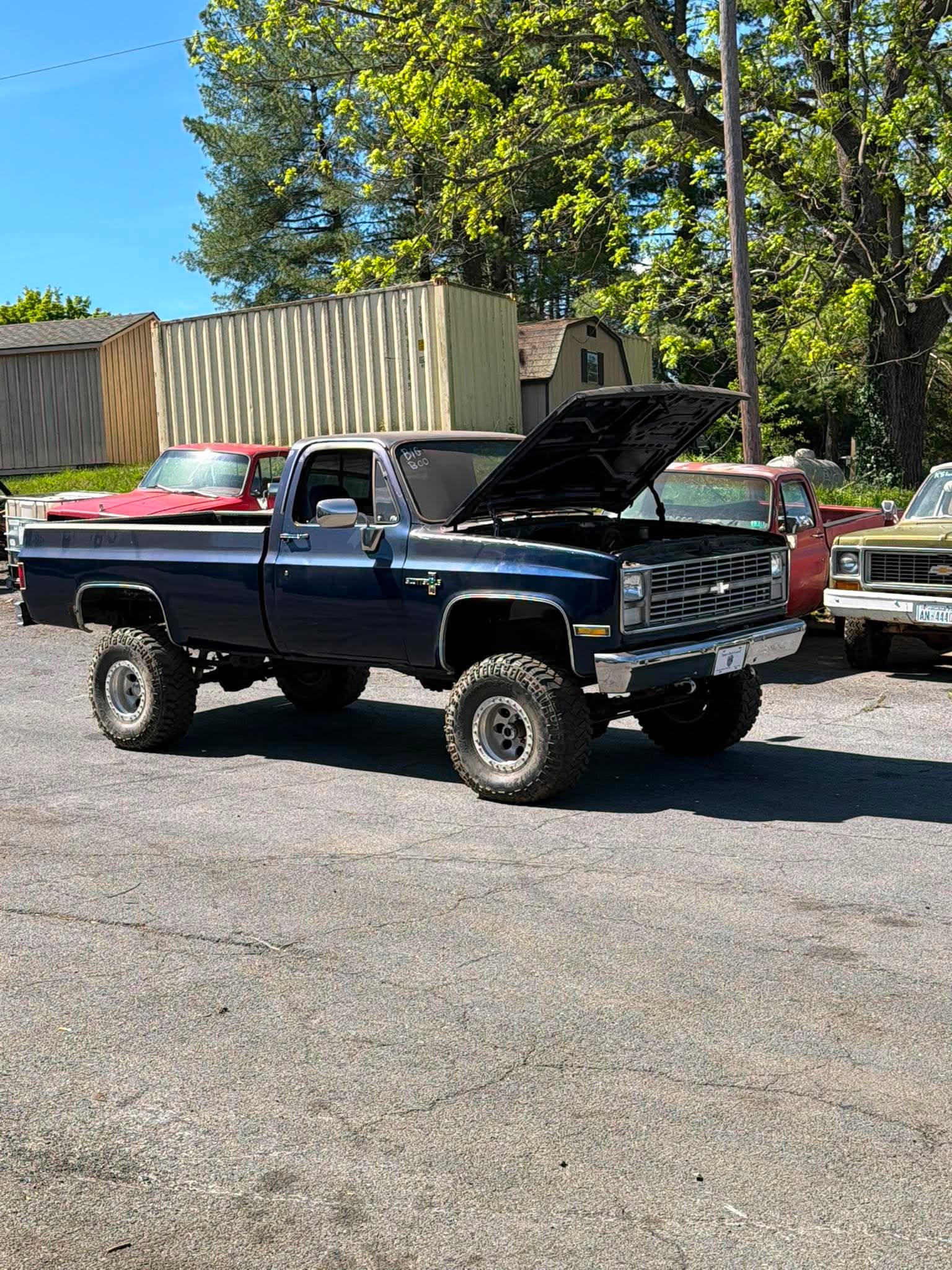 Lifted Chevy Square Body — Lifted dark blue classic Chevy square body pickup truck with the hood open, parked outside.