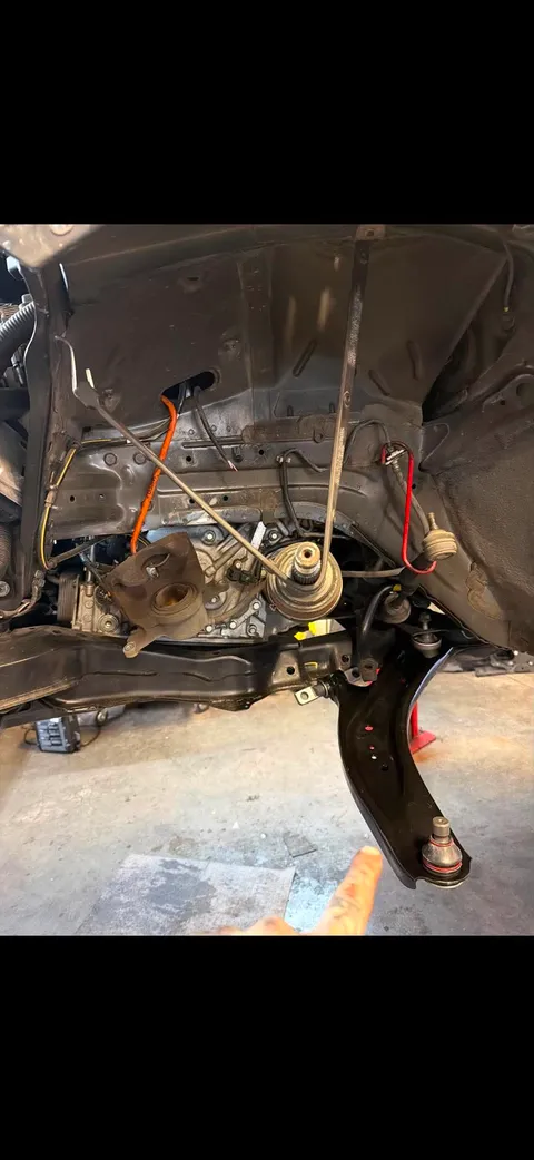 Suspension and Brakes Repair — Close-up of a vehicle's front suspension, brake caliper, and wheel hub assembly undergoing repair on a lift.