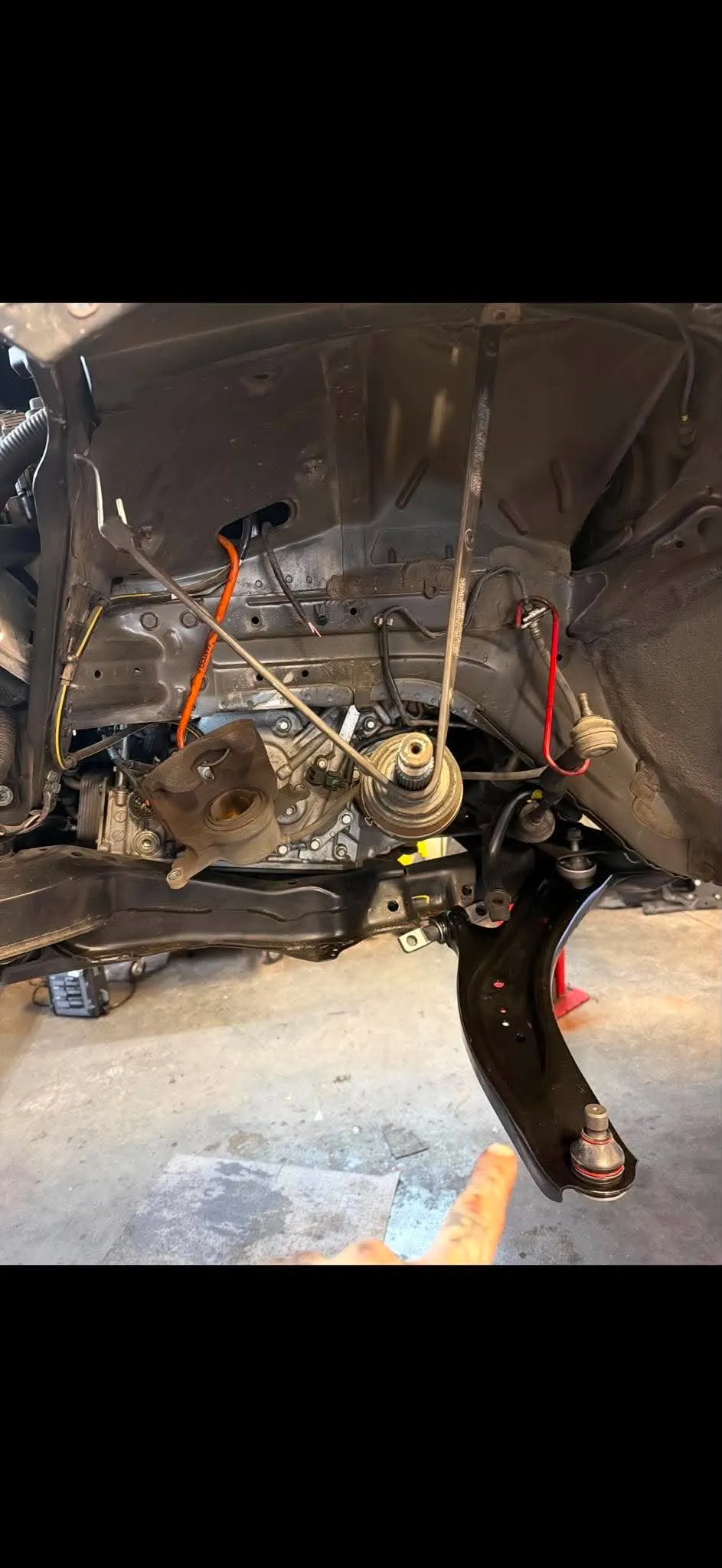 Suspension Repair — Close-up of a new black lower control arm and suspension components installed on a vehicle.